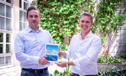 Photo of Thordur Reynisson and Rasmus Malmborg holding an iPad with the Briding Nordic Data publication frontpage.