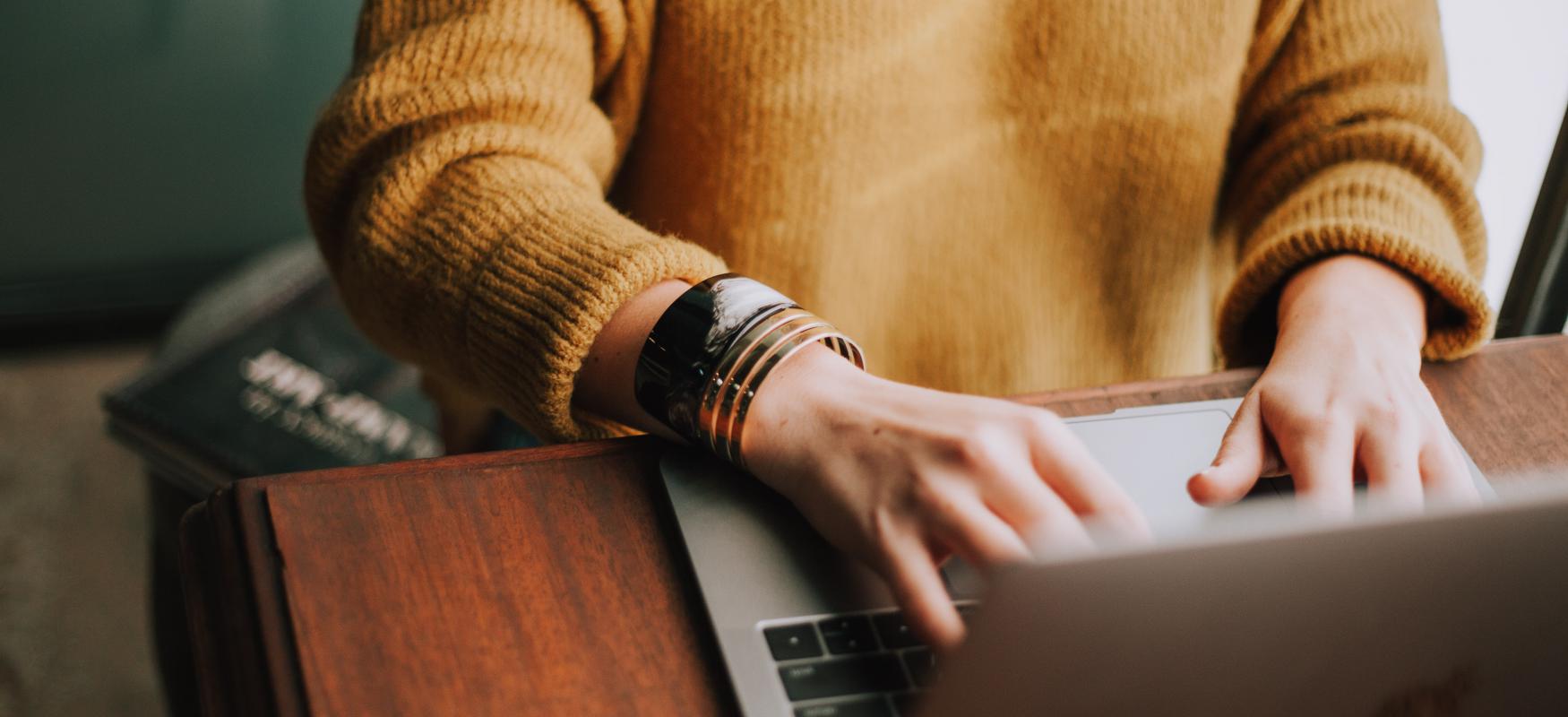 Woman sitting at a desk writing on her laptop