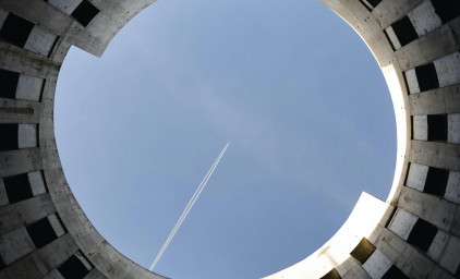 Looking up a round conctrete construction and seeing a plane flying over