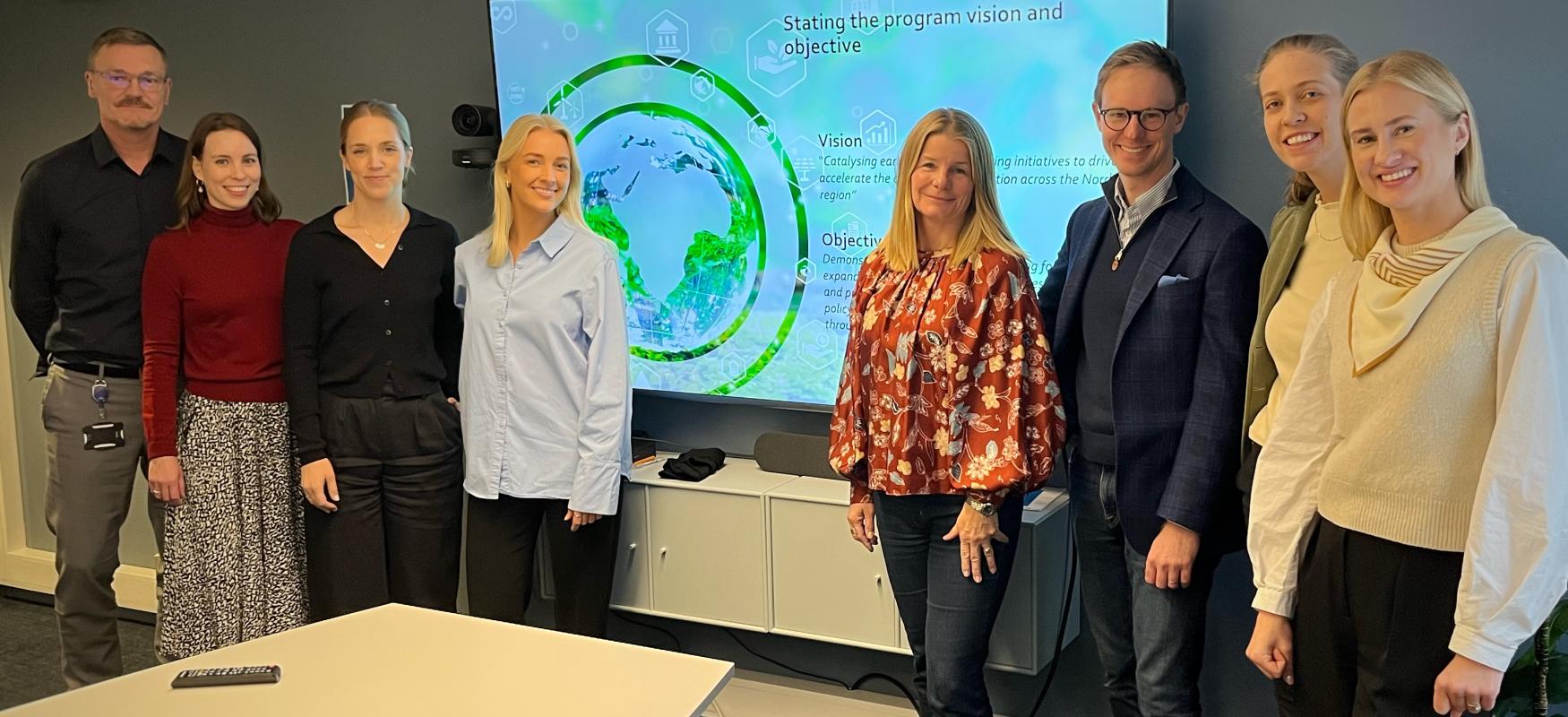 8 personer der står foran en præsentation