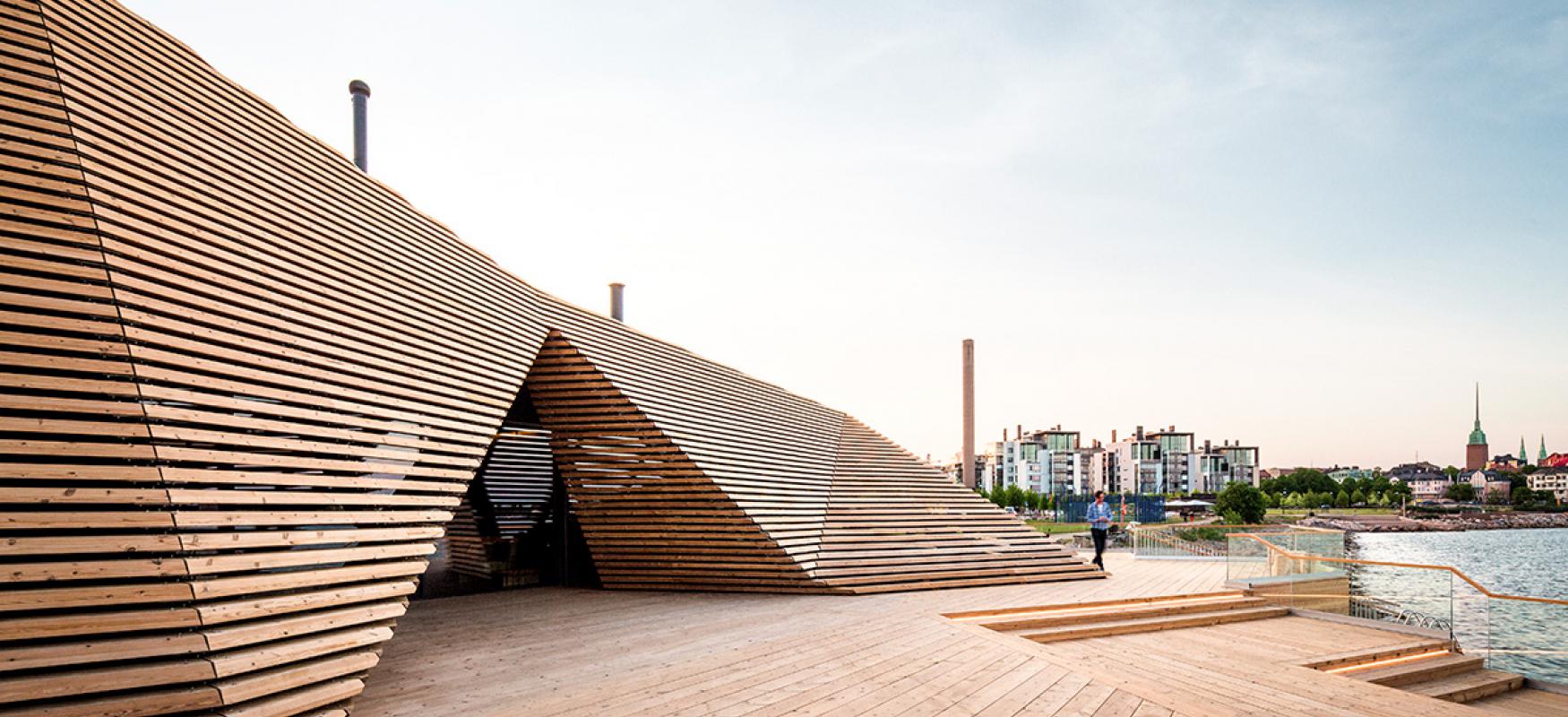 The wooden exterior of the Löyly sauna in Helsinki with the city in the background.
