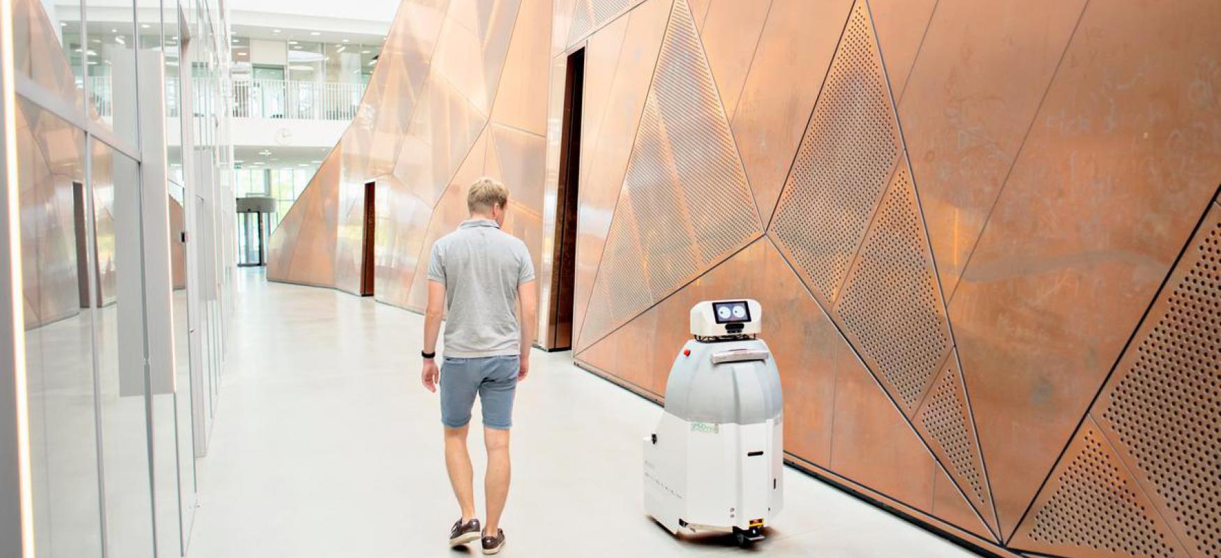 Man walking alongside a robot
