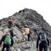 People hiking up a rocky mountain top.